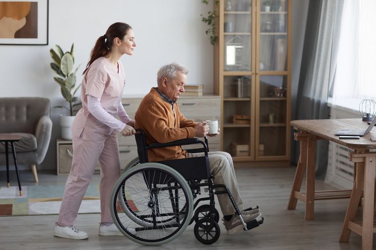 female caregiver assisting senior man in wheelchair